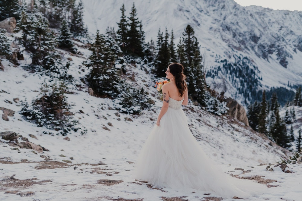 bride taking individual photo during her elopement at loveland pass